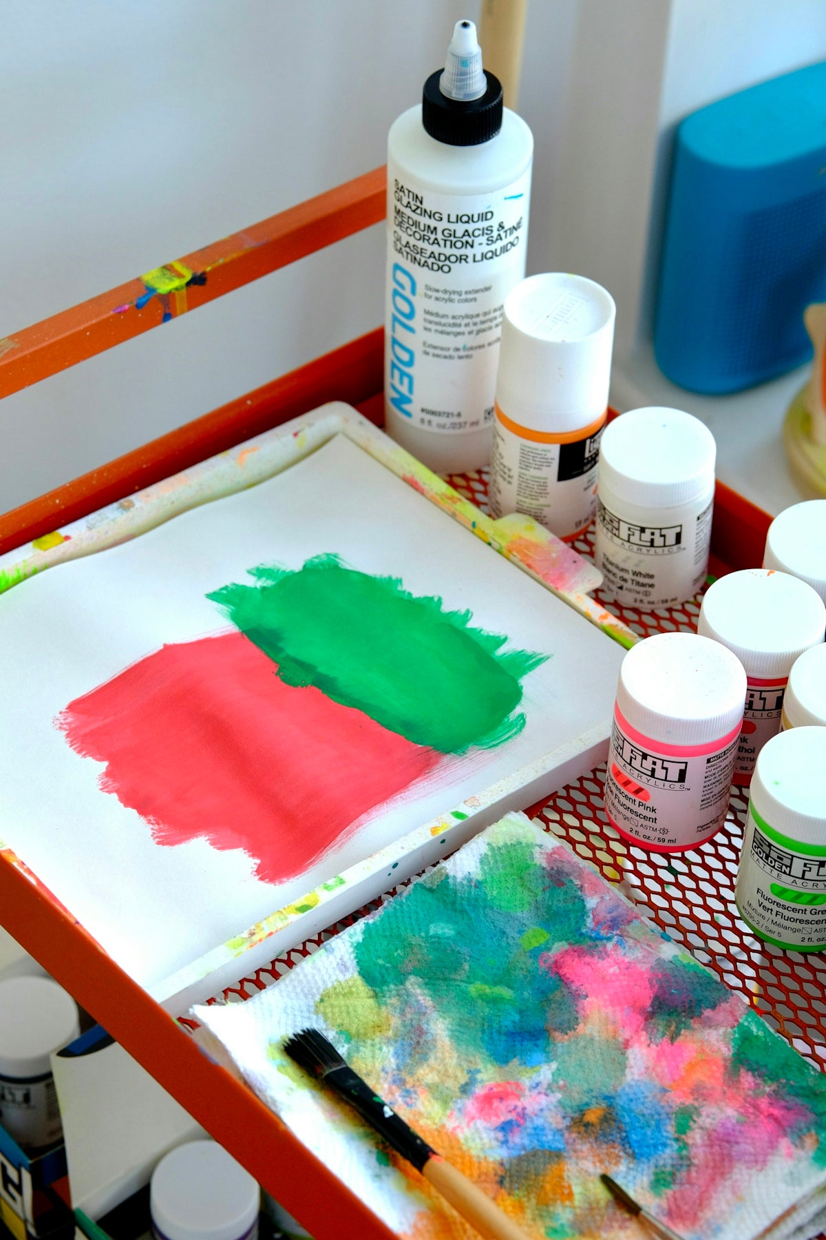 a table with paint, a brush, and a painting on it