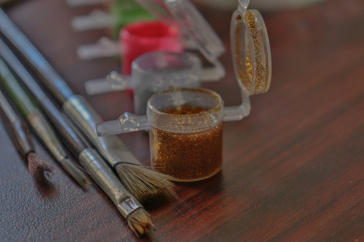 a wooden table topped with brushes and a cup filled with liquid