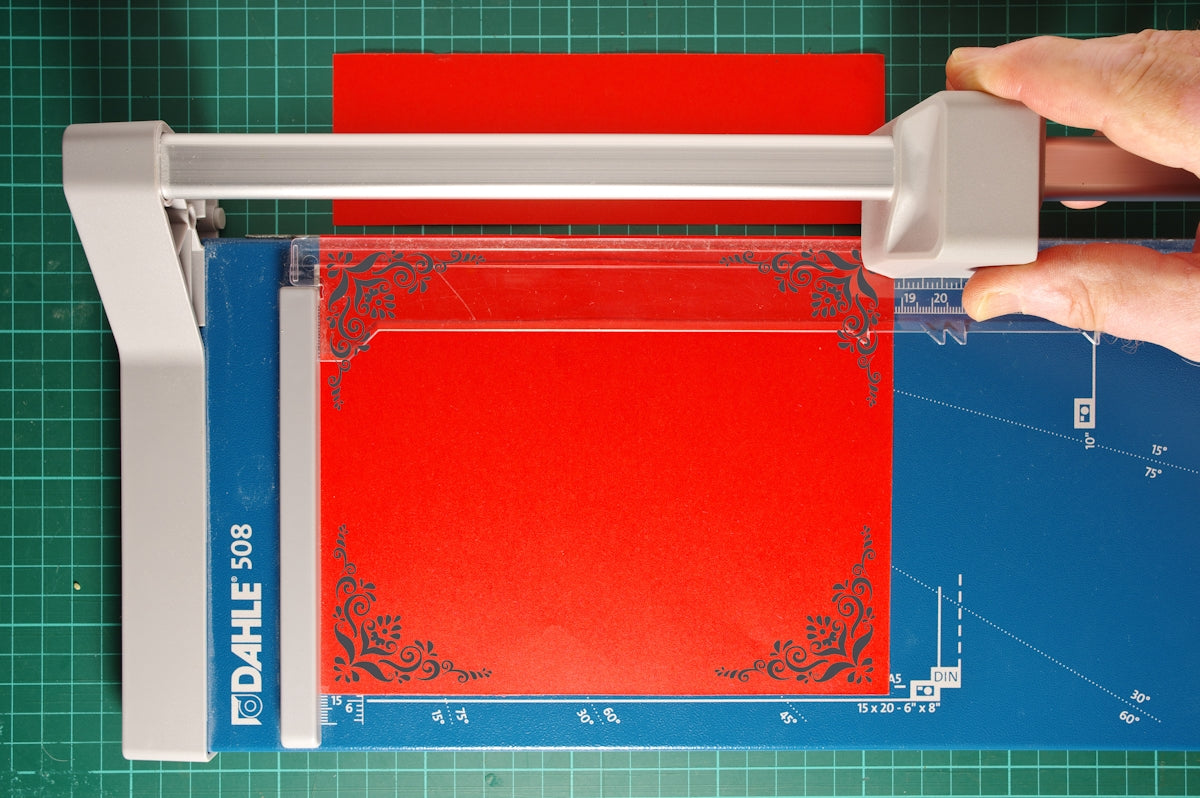 a person using a machine to cut a piece of paper