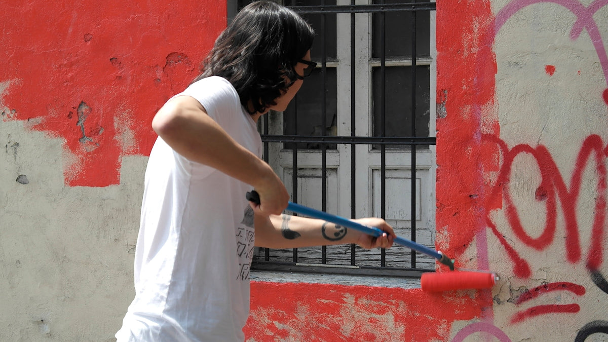 a man holding a paint roller in front of a window