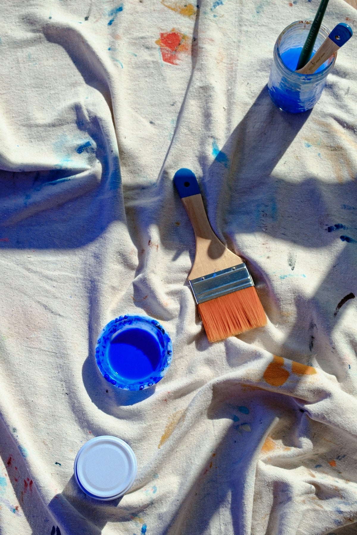 A table topped with paint and brushes on top of a white cloth