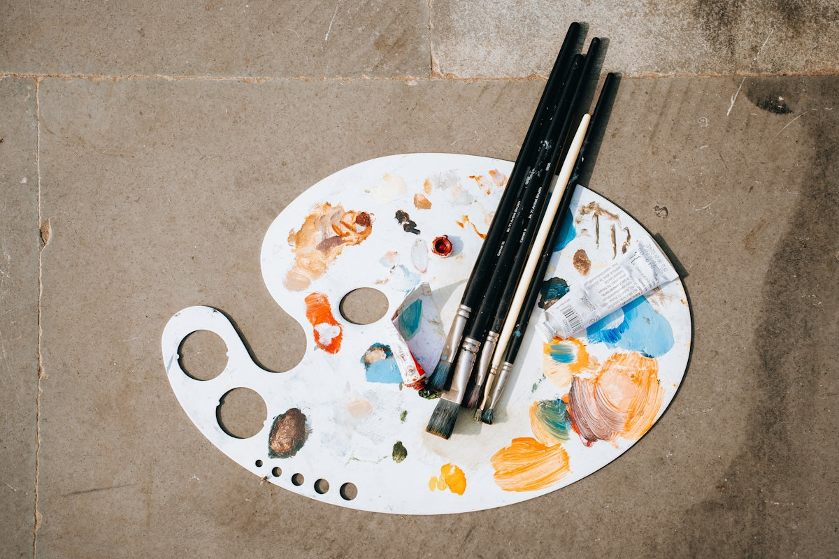 A paint palette with two black brushes on top of it