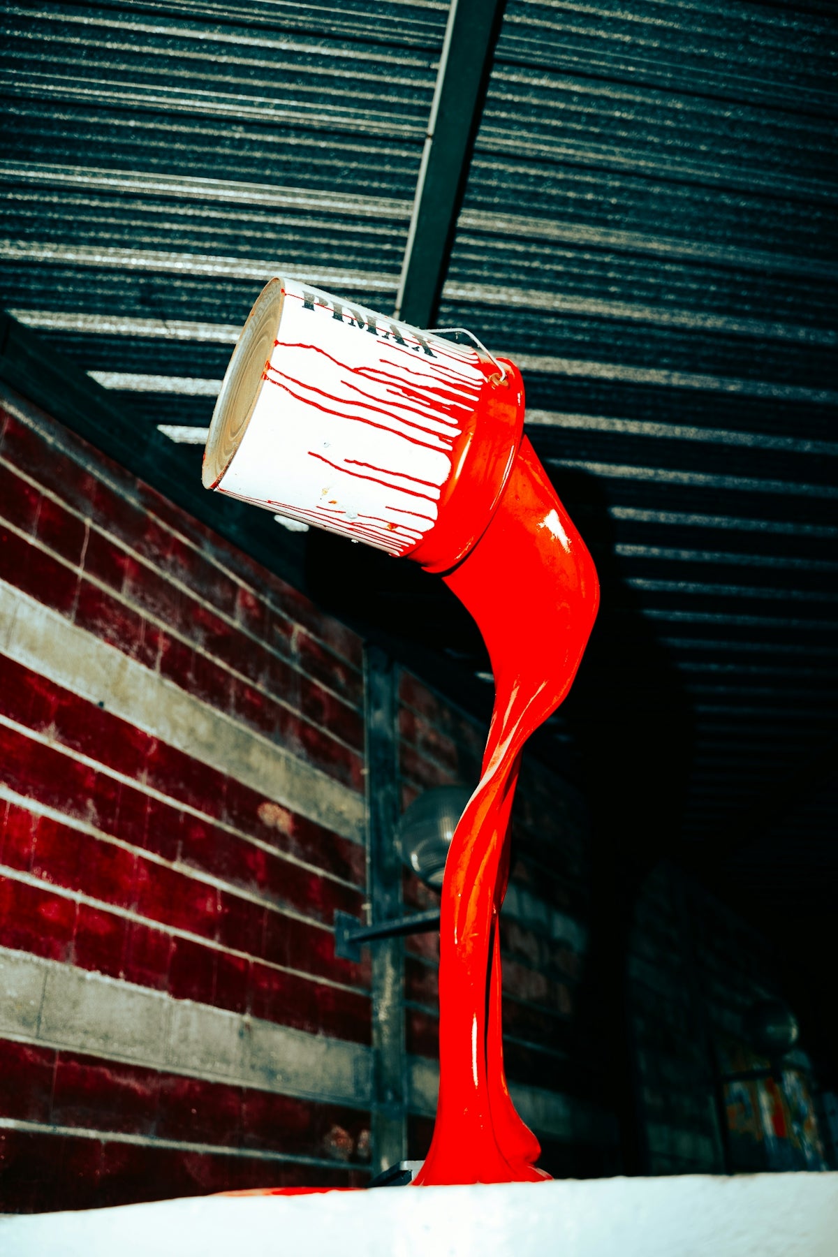 Red paint pouring from a bucket onto a surface.