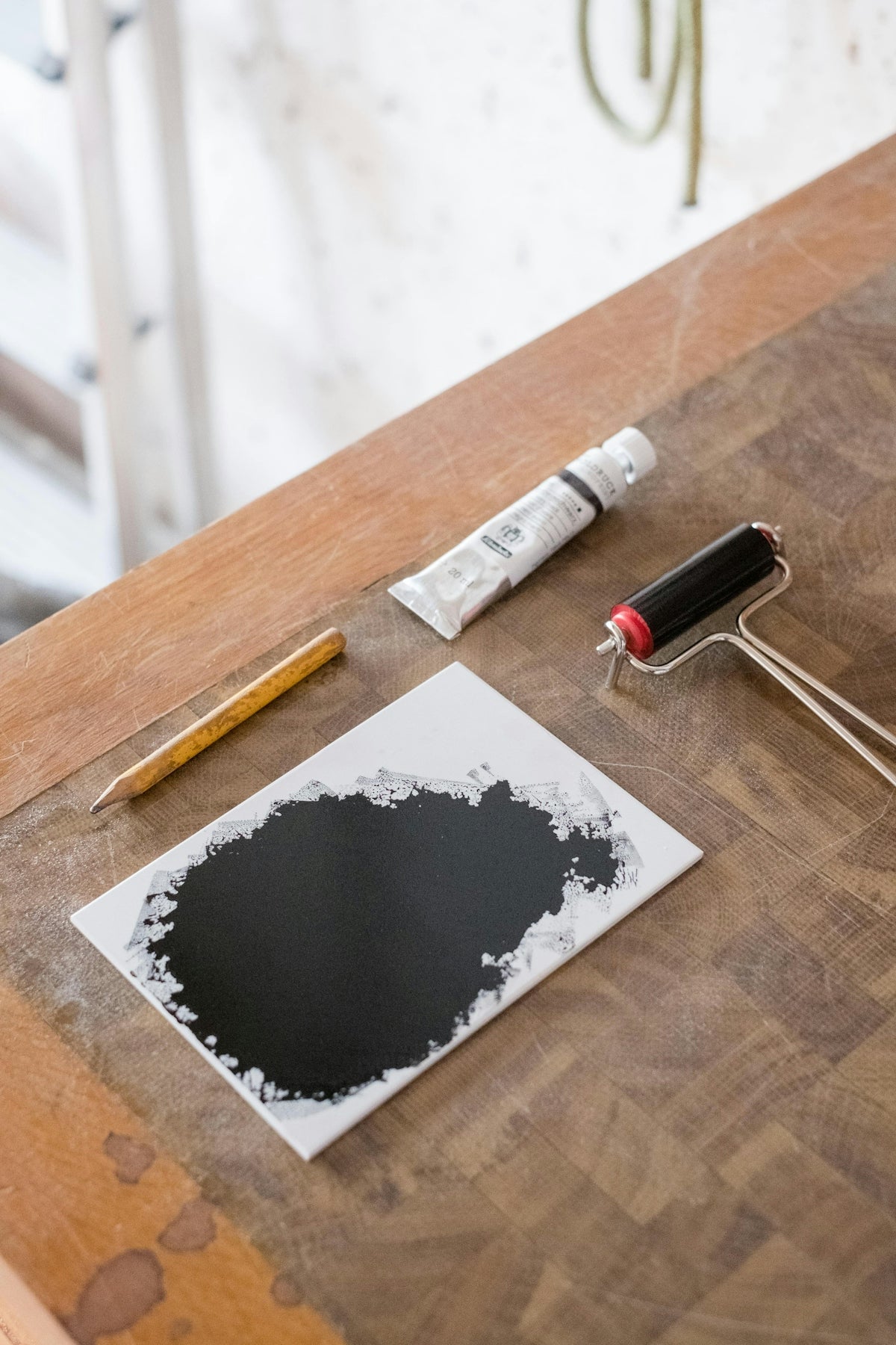 Black ink, brayer, and tube on a wooden table