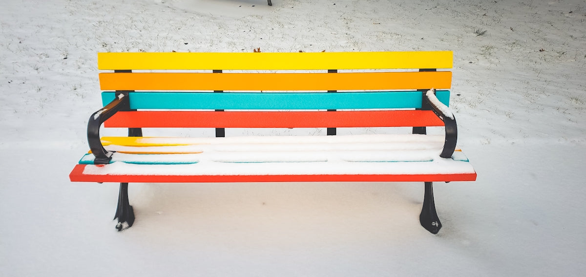 a multicolored bench sitting in the snow