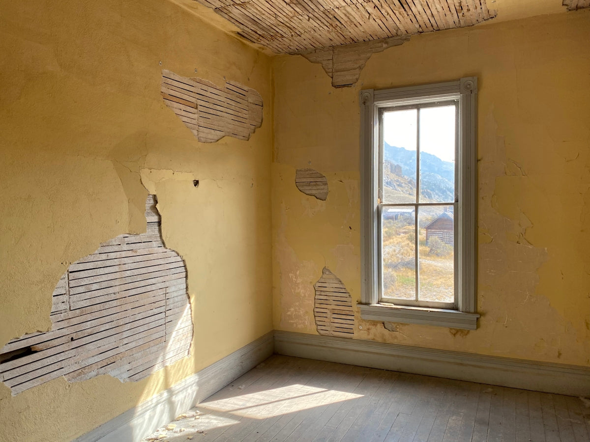 An abandoned room with decaying plaster walls.