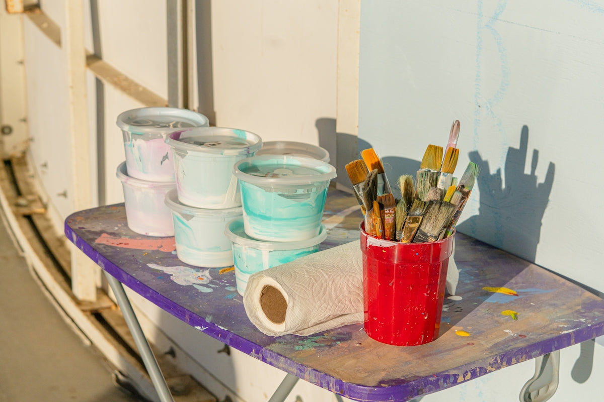Paint buckets and brushes sit on a table.